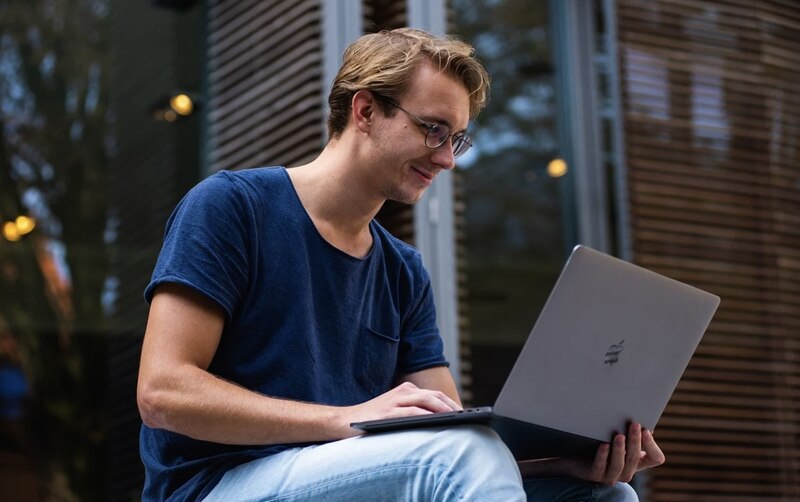 Un joven sentado en una escalera usando su laptop