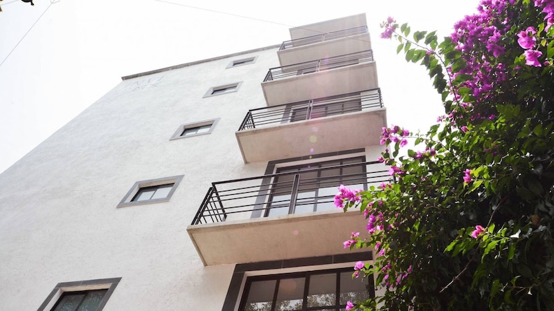 Edificio de apartamentos moderno con fachada blanca y balcones con barandillas de metal negro.