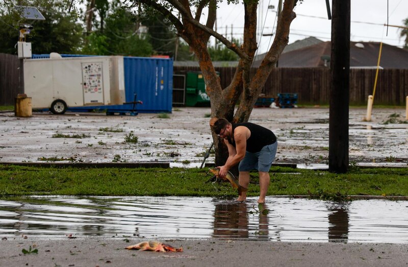 Un hombre captura un pez en una calle inundada