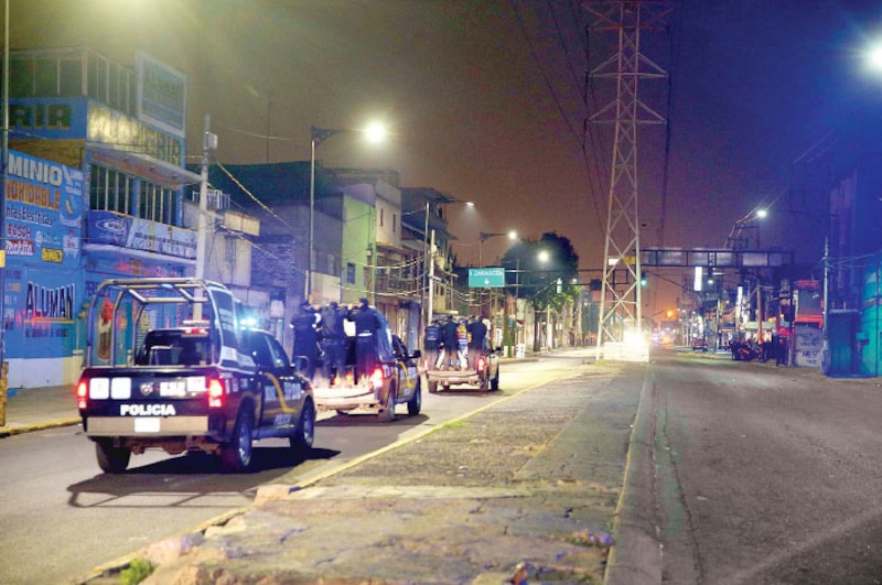 La policía detiene a un grupo de personas en una calle oscura.
