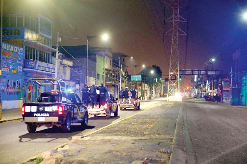 La policía detiene a un grupo de personas en una calle oscura.