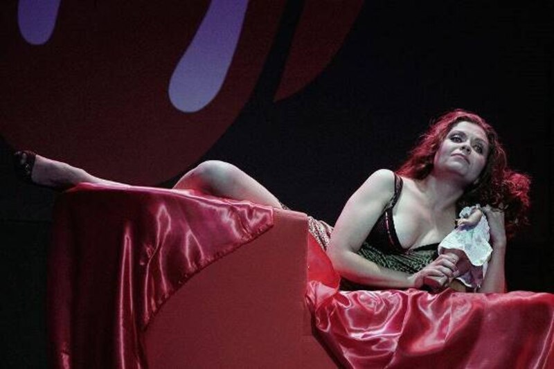 Mujer en vestido rojo acostada en una cama con un peluche en la mano
