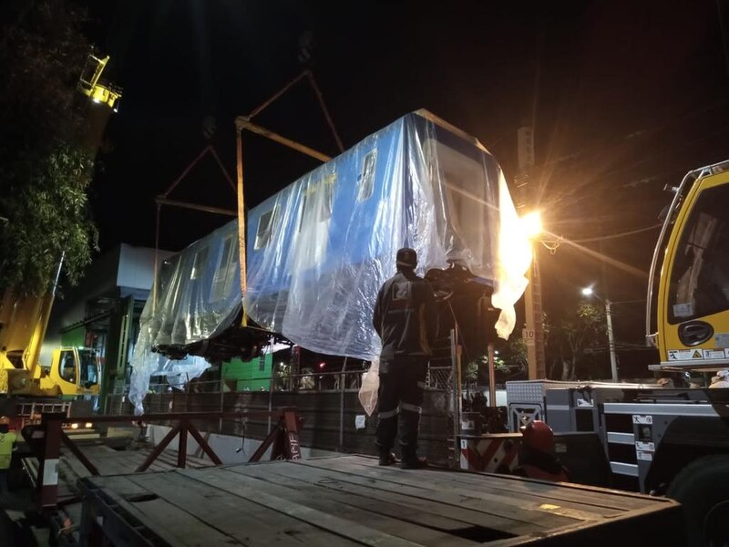 Un tren es izado por una grúa en la noche