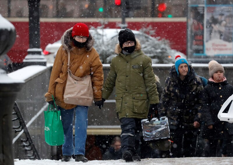 Madre e hijo caminan por la calle en un día de nieve.