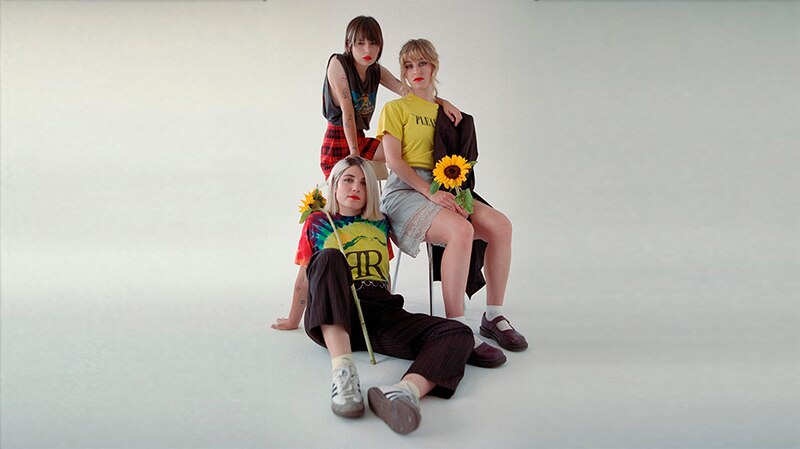 Las integrantes de HAIM posan para una foto con girasoles.