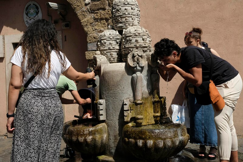 Personas bebiendo agua de una fuente pública