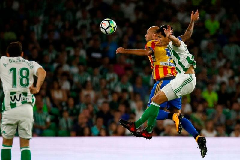Dos jugadores de fútbol se disputan un balón aéreo.