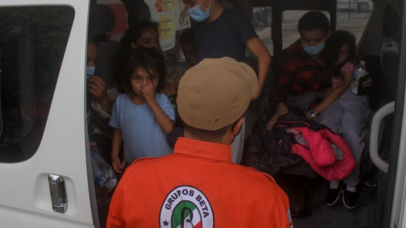 Rescatistas ayudan a migrantes centroamericanos a abordar un autobús en la frontera entre México y Estados Unidos.