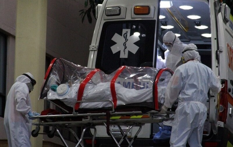 Paciente con COVID-19 es trasladado en camilla a una ambulancia