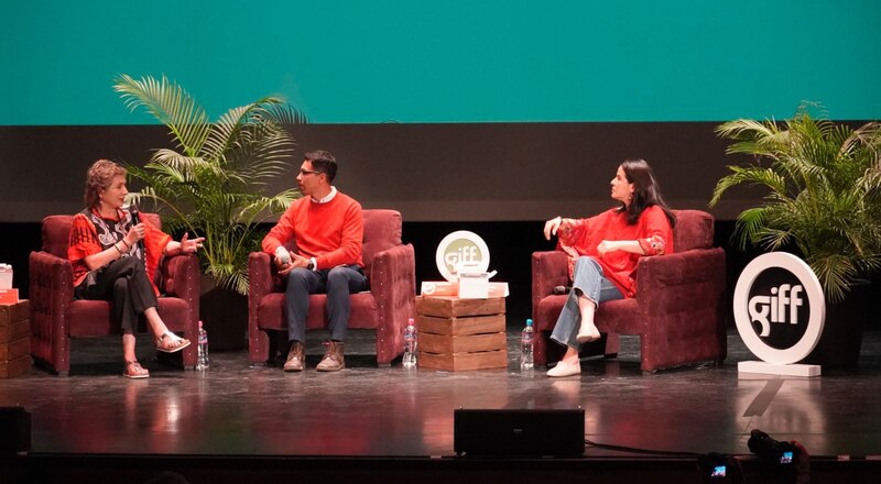 Tres personas en un escenario conversando animadamente.