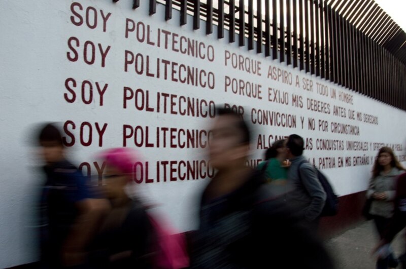 Estudiantes politécnicos caminan frente a un mural en la Ciudad de México.