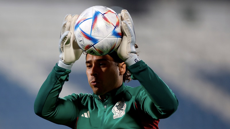 El portero mexicano Guillermo Ochoa detiene un balón durante un partido de fútbol.