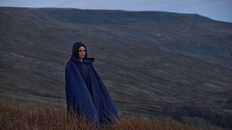 Mujer con capa azul en un campo