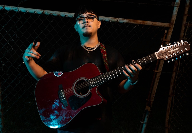 Rohmy Martínez la nueva voz del regional tumbado, sosteniendo una guitarra
