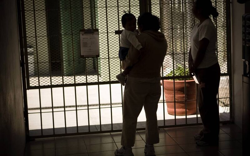 Madre e hijo migrantes esperan en la frontera