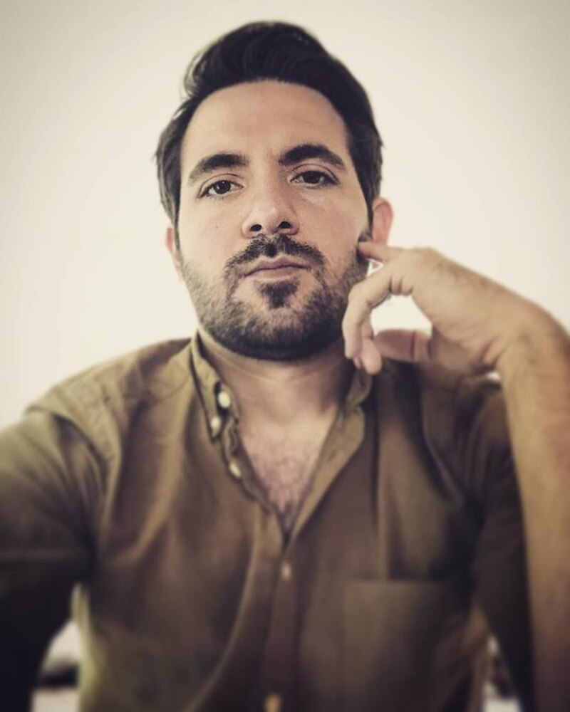 Un hombre con barba y cabello oscuro se toma una selfie