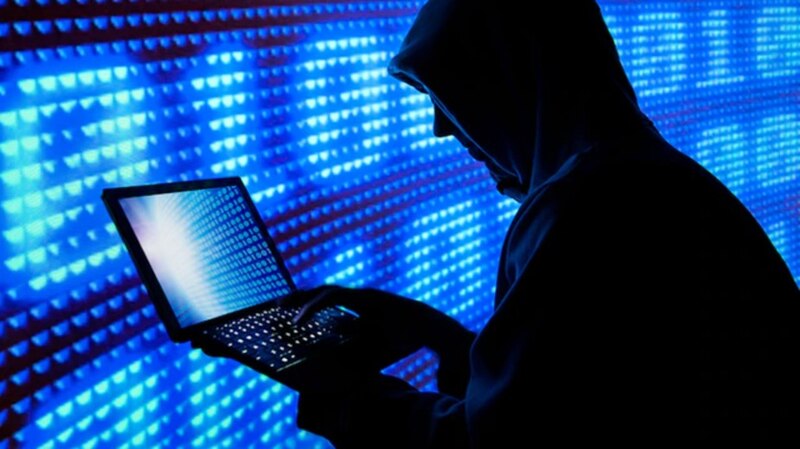 Ciberdelincuente encapuchado usando una computadora portátil