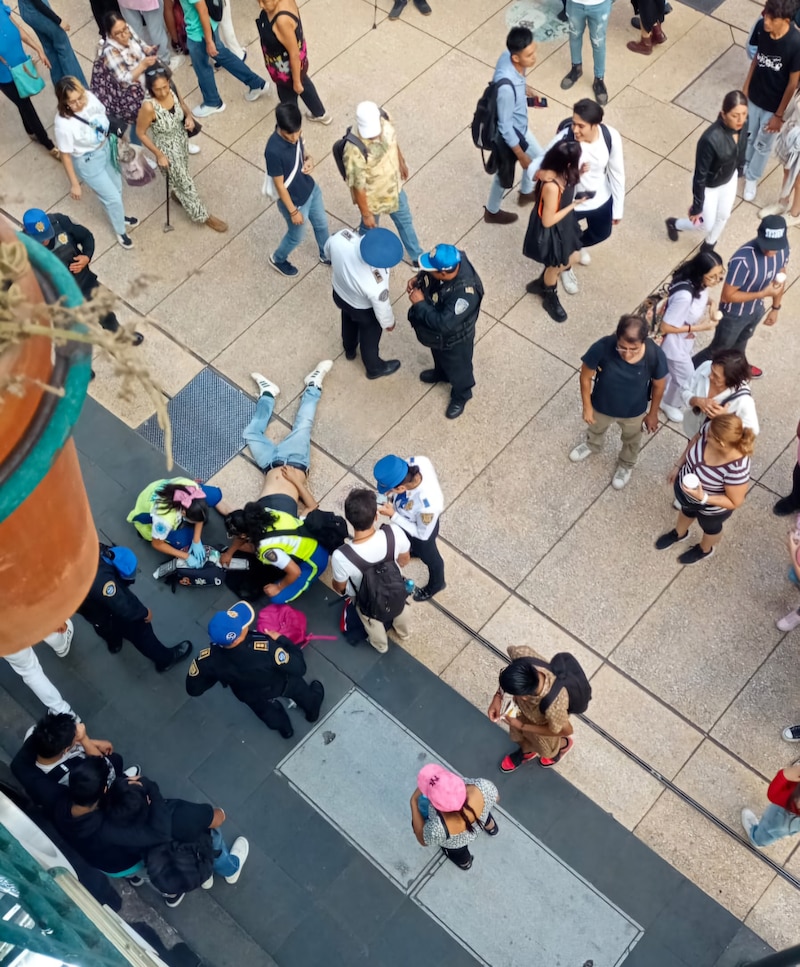 Un hombre es atendido por paramédicos en el suelo mientras la policía rodea la escena.