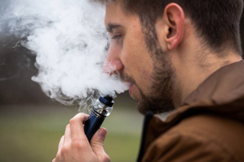 Hombre joven fumando un cigarrillo electrónico