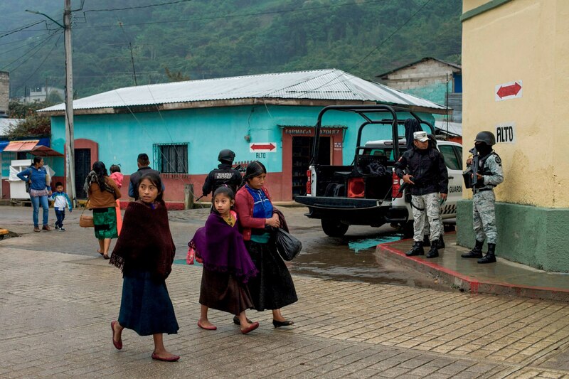 Indígenas guatemaltecas caminan por una calle adoquinada en un pueblo.