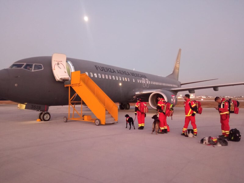 Rescatistas mexicanos con perros de búsqueda y rescate listos para abordar un avión de la Fuerza Aérea Mexicana.