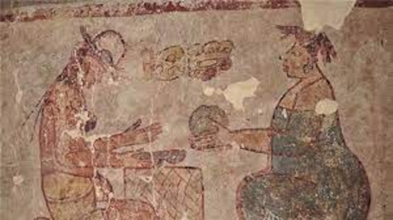 Mujer maya ofrece comida a un hombre sentado