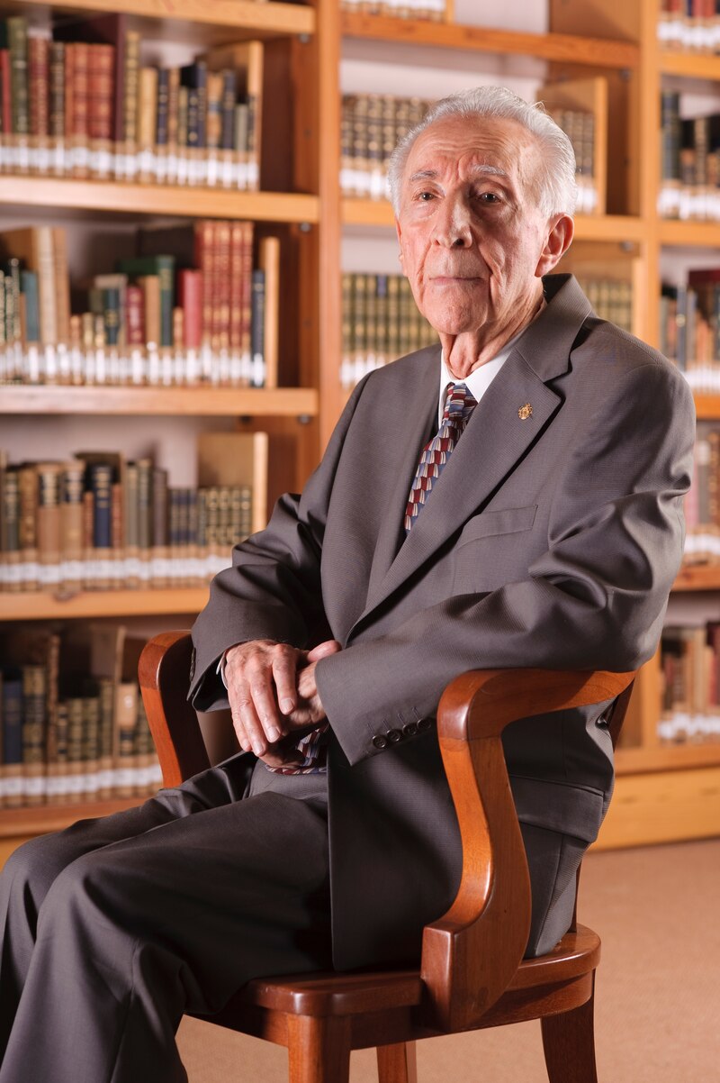 Un anciano sentado en una silla en una biblioteca