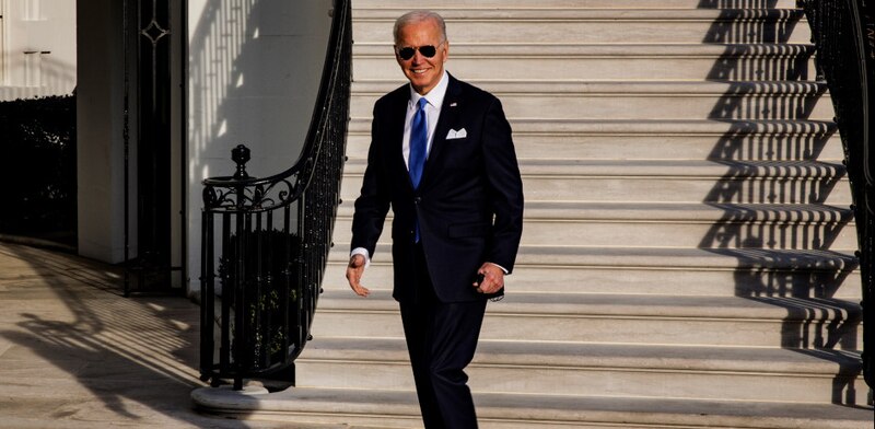 El presidente Biden sonríe mientras baja las escaleras de la Casa Blanca