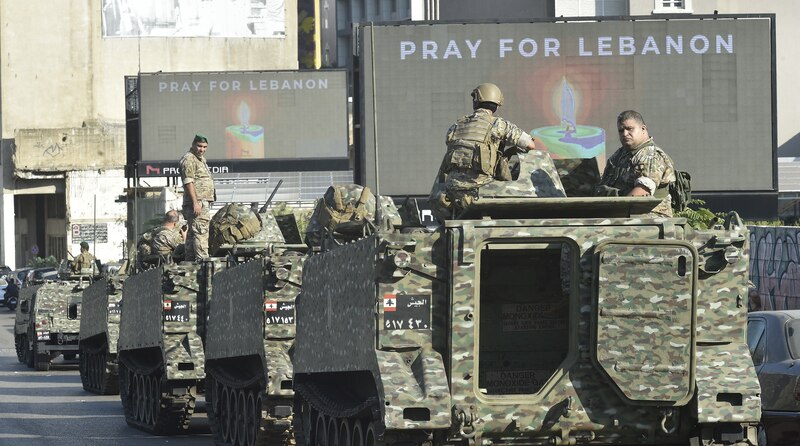 Soldados libaneses en un tanque con la leyenda "Pray for Lebanon" en una pantalla detrás de ellos