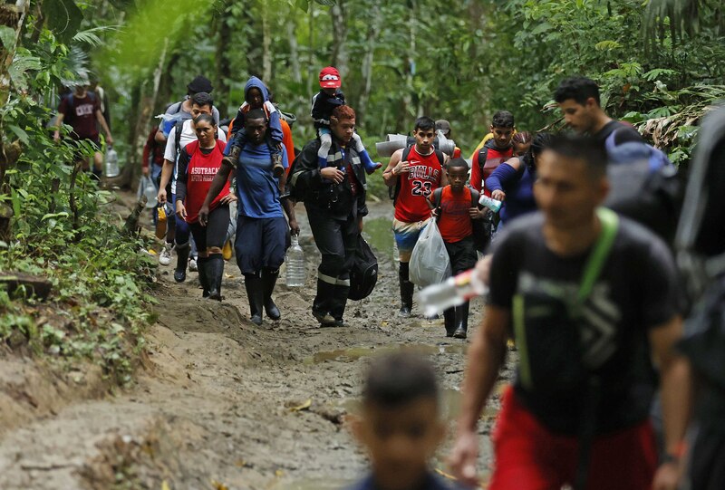 Migrantes caminan por un sendero en la selva