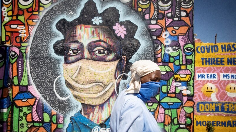 Mujer con mascarilla pintada en un mural