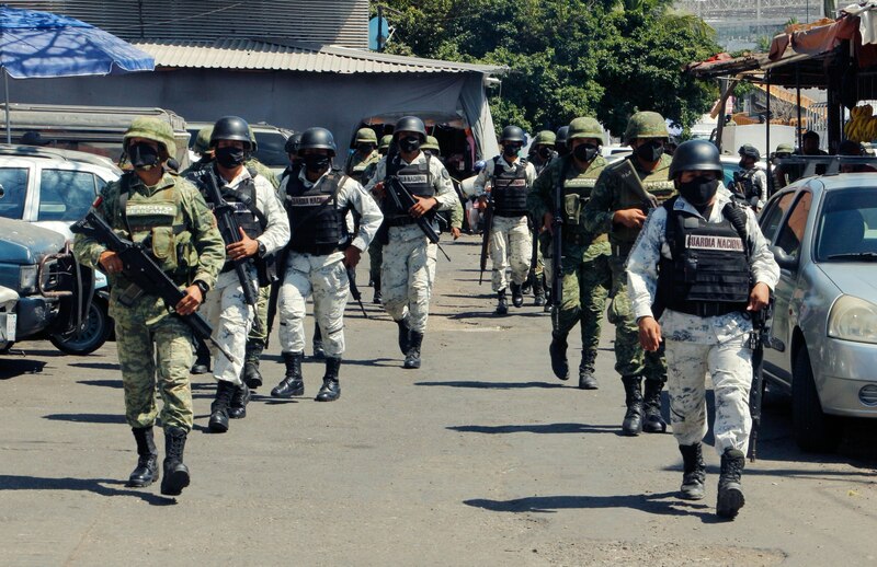 Title: Militares mexicanos patrullan una calle en una ciudad