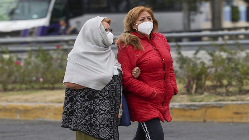 Dos mujeres caminan por la calle con mascarillas