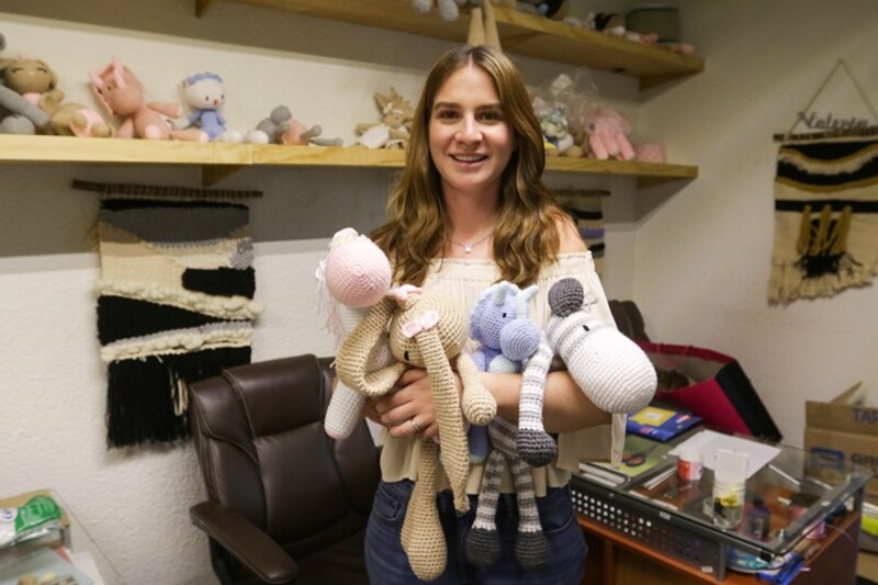 Mujer sosteniendo peluches tejidos a mano
