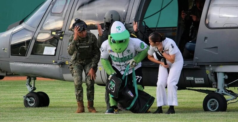 La mascota de los Tigres del Licey saluda a los marinos antes de abordar un helicóptero