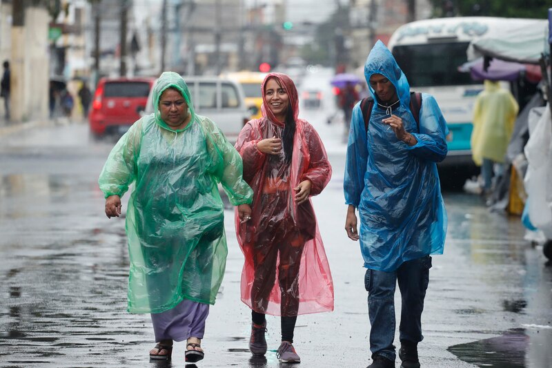 Tres personas caminan bajo la lluvia