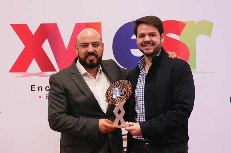 Dos hombres sonríen mientras sostienen un premio.