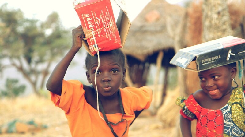 Dos niñas africanas llevan cajas de cartón en la cabeza