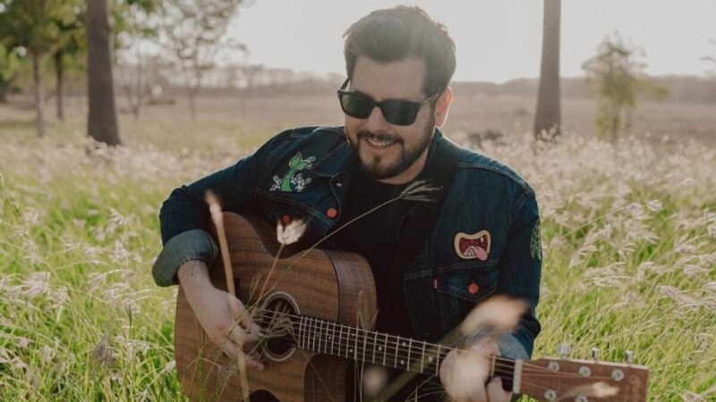 Un músico tocando la guitarra en un campo