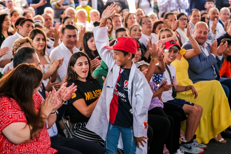 Un niño vestido de doctor saluda a la multitud