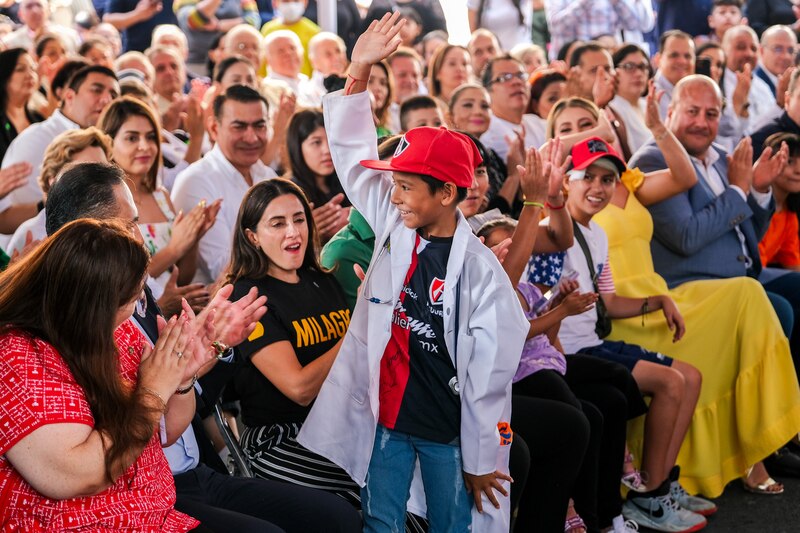 Un niño vestido de doctor saluda a la multitud