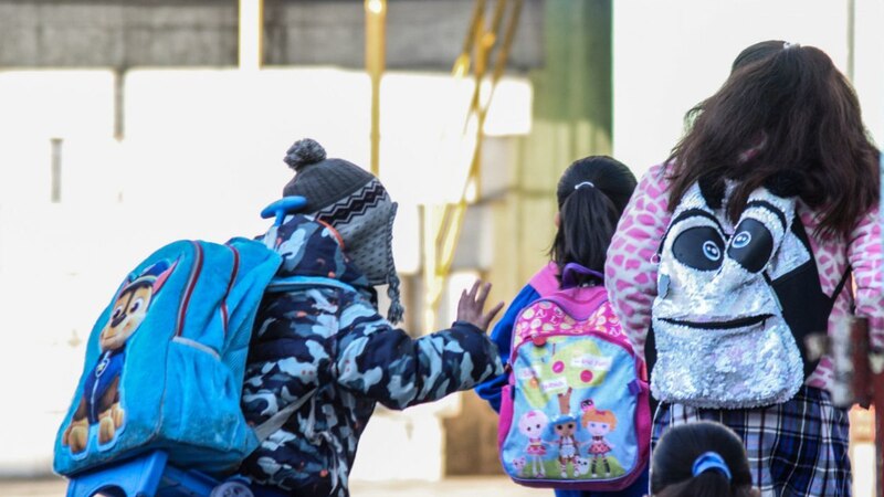 Niños de espaldas con mochilas
