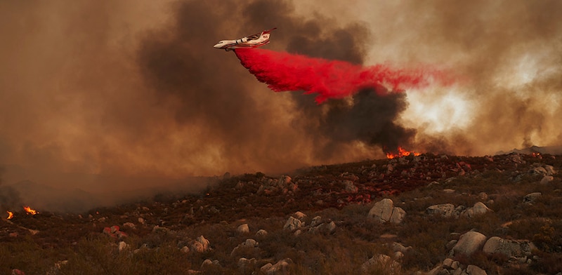 Un avión cisterna descarga agua sobre un incendio forestal