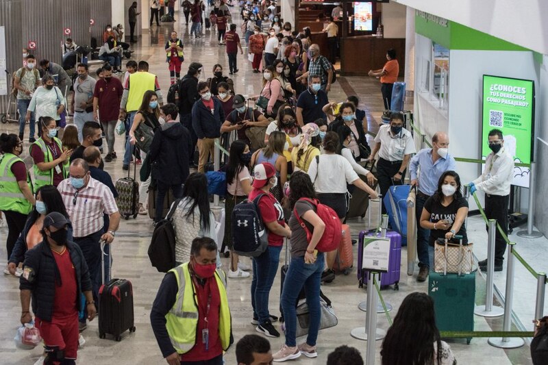 Multitud de personas en el aeropuerto con mascarillas