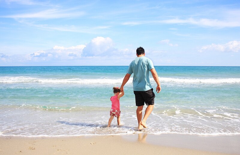 Padre e hija caminando en la playa