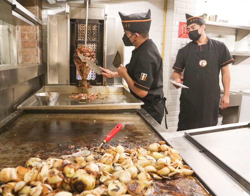 Un chef corta carne de un trompo.