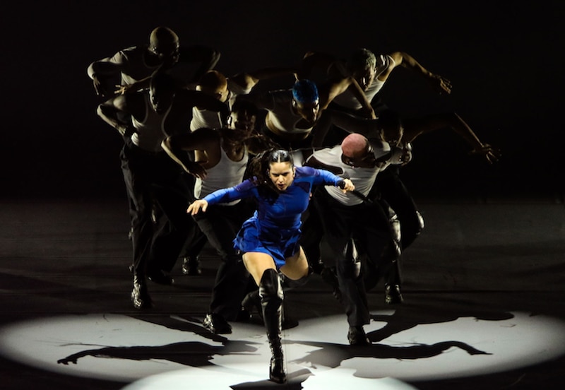 Una bailarina de ballet realiza una pirueta rodeada de bailarines de apoyo.