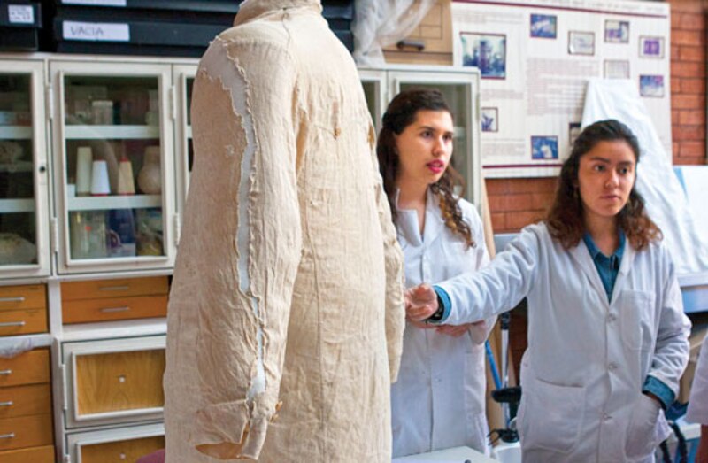 Dos mujeres en un laboratorio examinan una camisa histórica