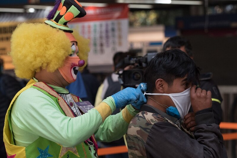 Un payaso ayuda a un hombre a ponerse una mascarilla