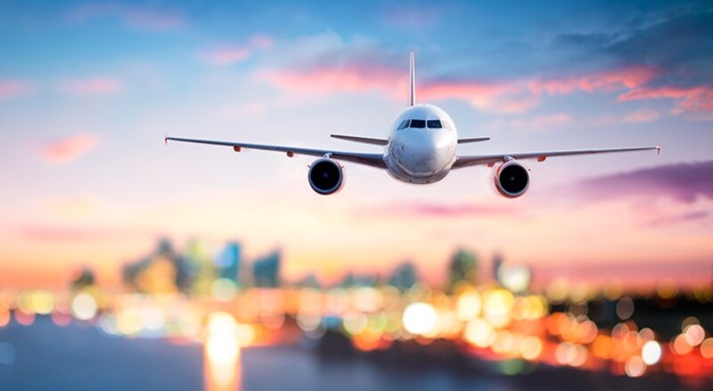 Un avión despegando de una ciudad al atardecer